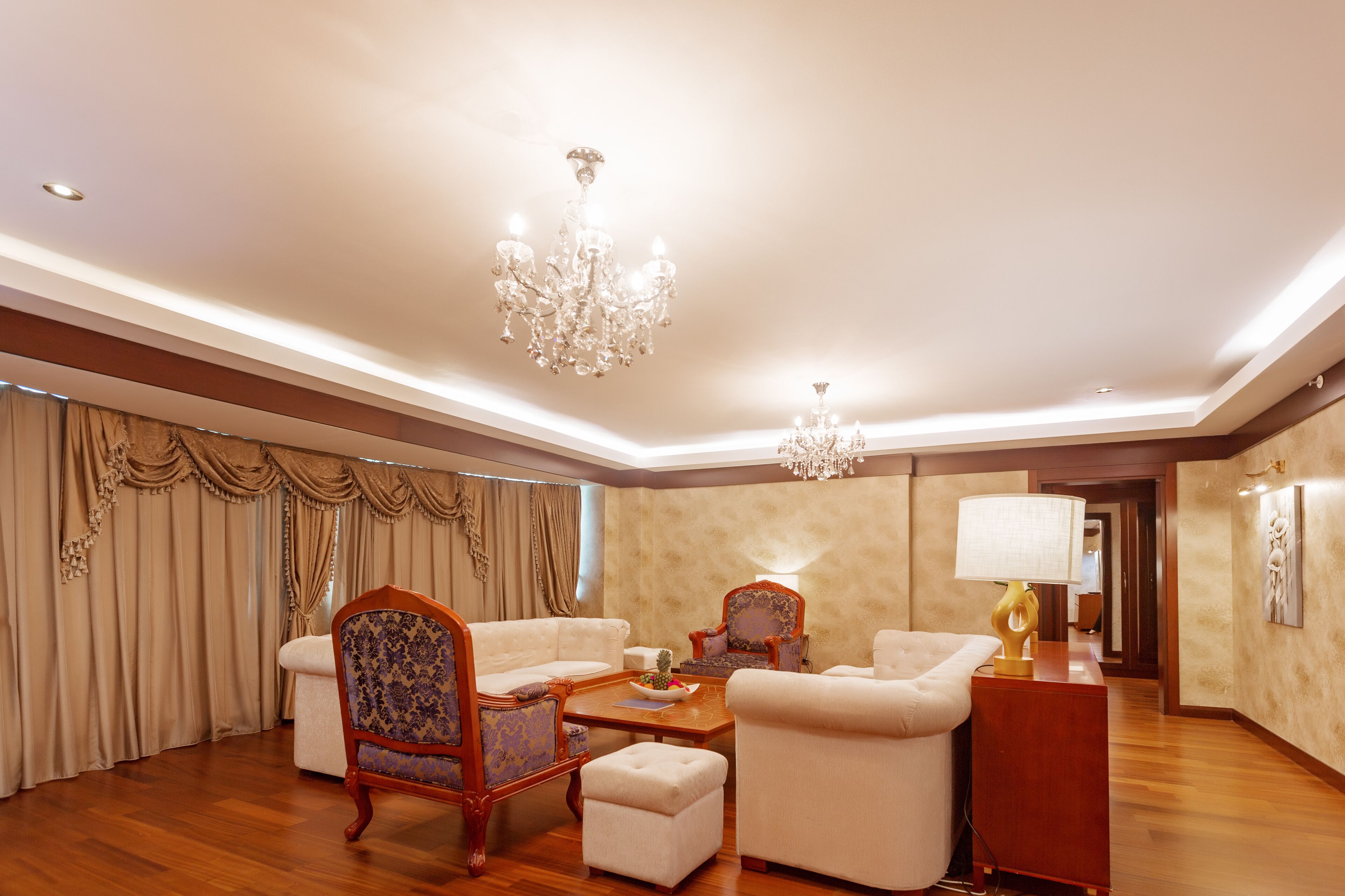 A spacious living room with a chandelier, a sofa, a chair, and a coffee table.