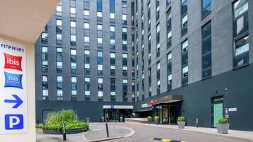 A modern hotel building with a prominent entrance, a parking sign, and a clear view of the entrance area.