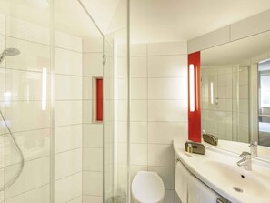 Une salle de bain moderne avec une douche à parois de verre, des toilettes blanches et un lavabo avec un miroir.