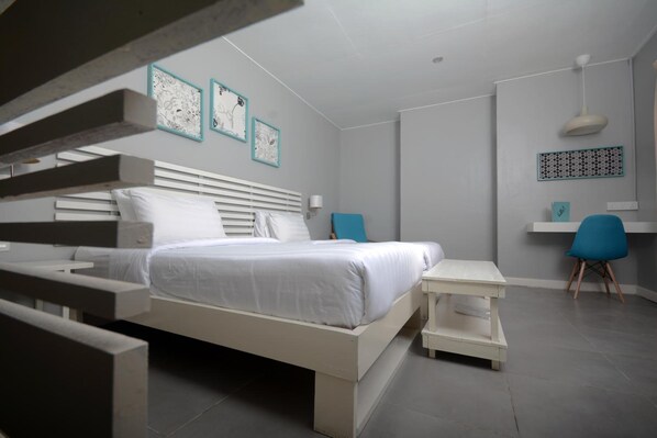 A modern bedroom with a bed, bedside tables, a desk, and a chair.