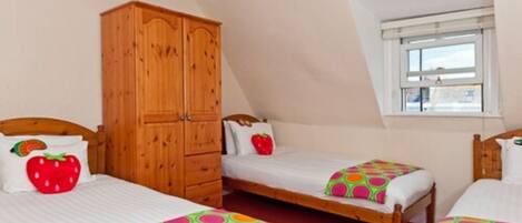 A room with two single beds, a wooden wardrobe, and a window with a view.