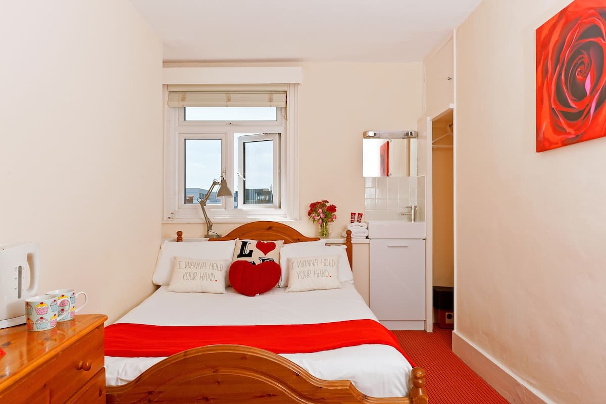 Un dormitorio ordenado con cama, mesita de noche y ventana.