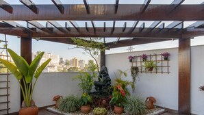 A rooftop garden with potted plants, a small rock waterfall, and a city view. - Faro Hotel São José dos Campos (São José dos Campos)