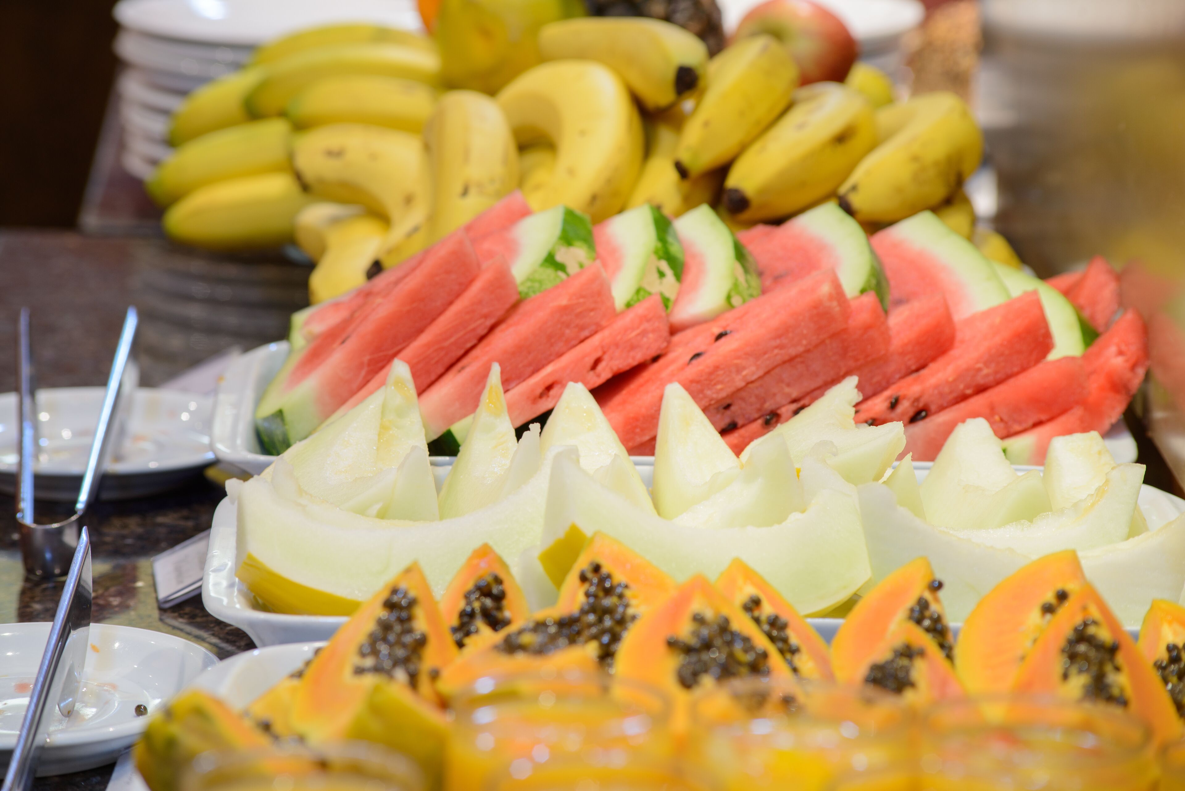 A buffet with various fruits including watermelon, cantaloupe, papaya, and bananas.