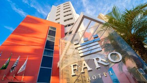 A modern building with a prominent "FARO HOTEL" sign, featuring a glass facade reflecting the sky and surrounding buildings. - Faro Hotel São José dos Campos (São José dos Campos)