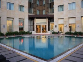 Un hotel con piscina central, acceso cubierto y diseño arquitectónico moderno.