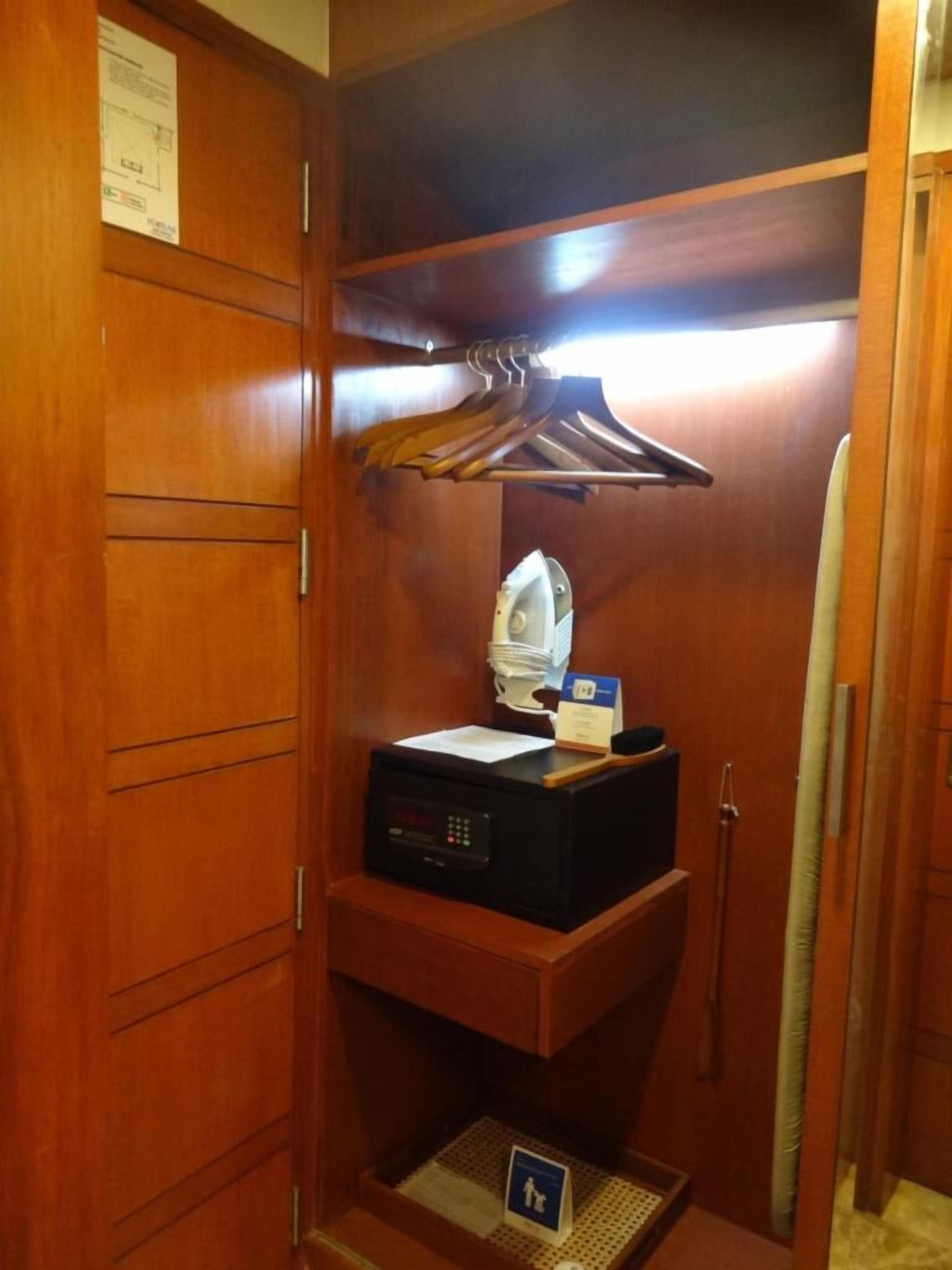 A compact, wood-paneled room with a built-in microwave, a small shelf with a tissue box, and a hanging garment rack.