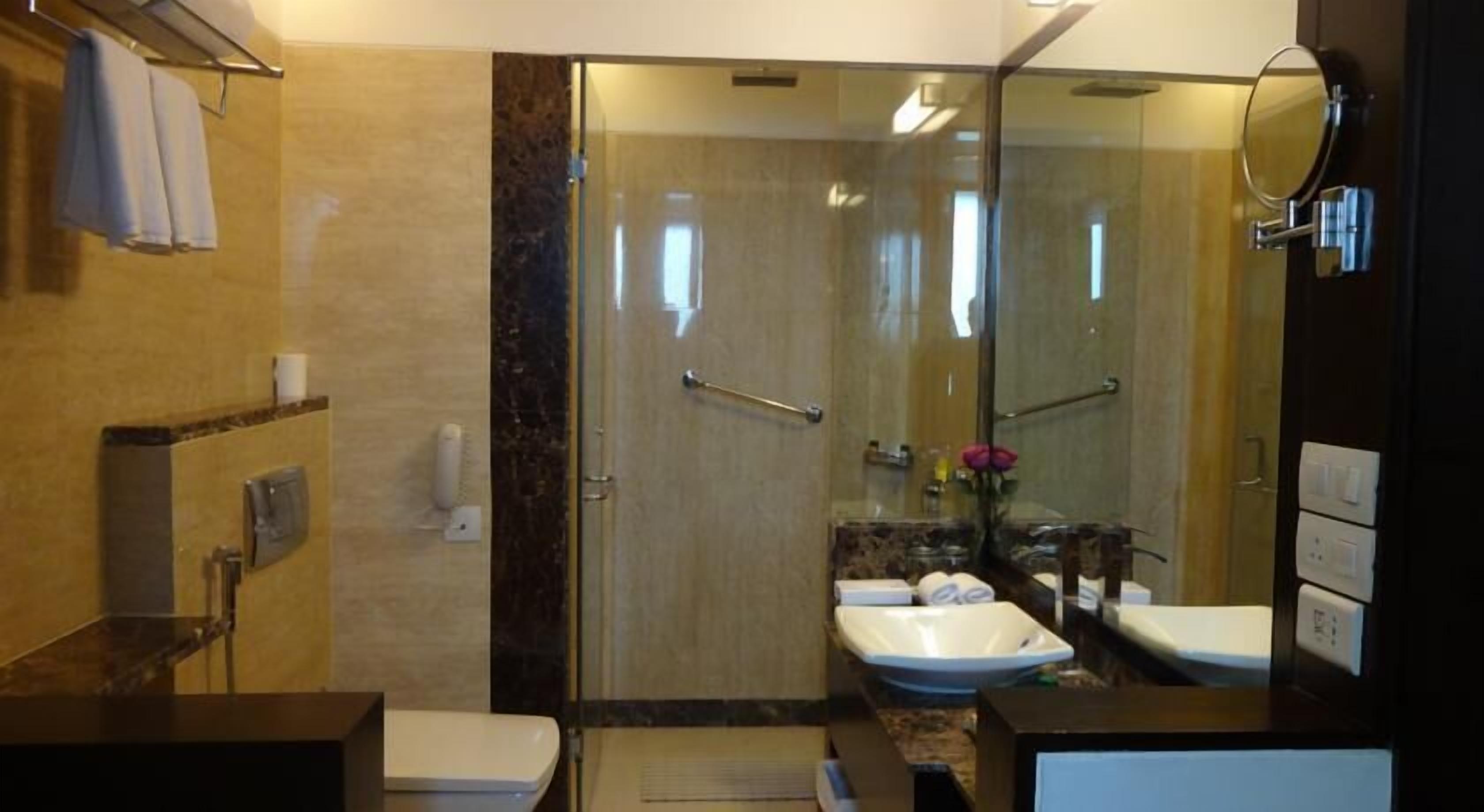 Une salle de bain moderne avec une douche à parois de verre, deux lavabos et un meuble-lavabo avec un miroir.