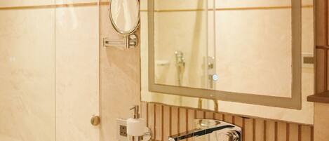 A bathroom with a large mirror, a sink, and a towel dispenser.