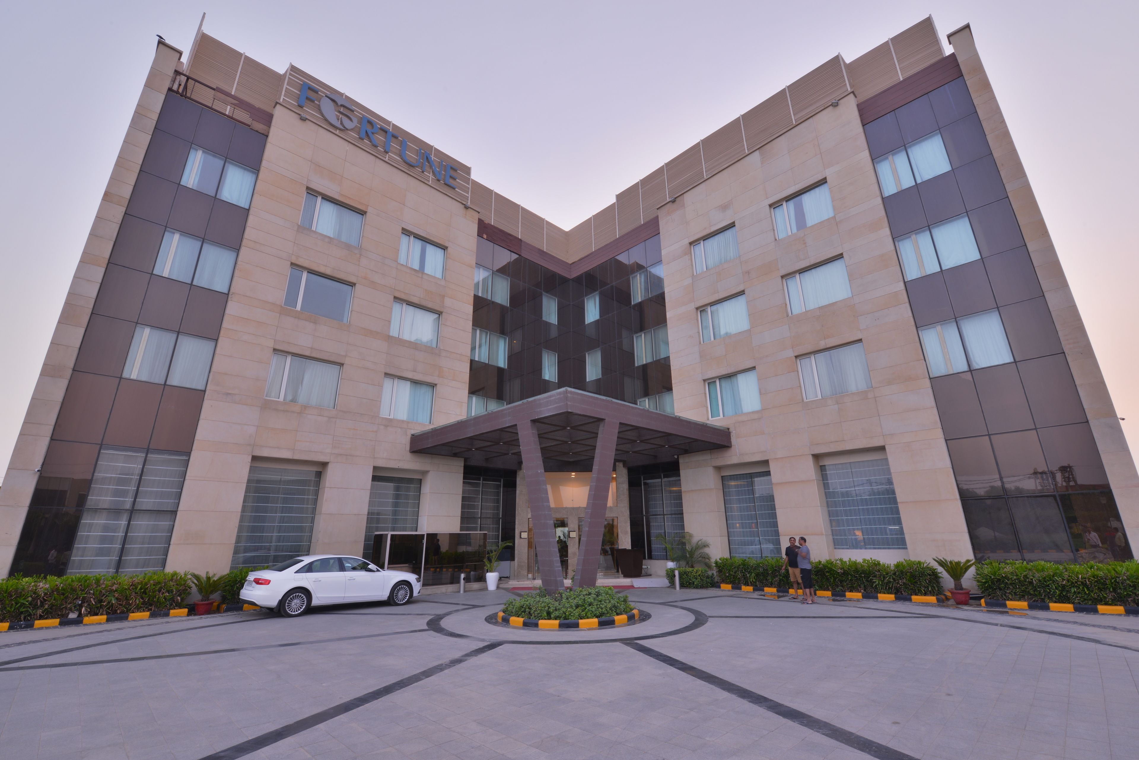 A modern building with a prominent entrance and a car parked in front.