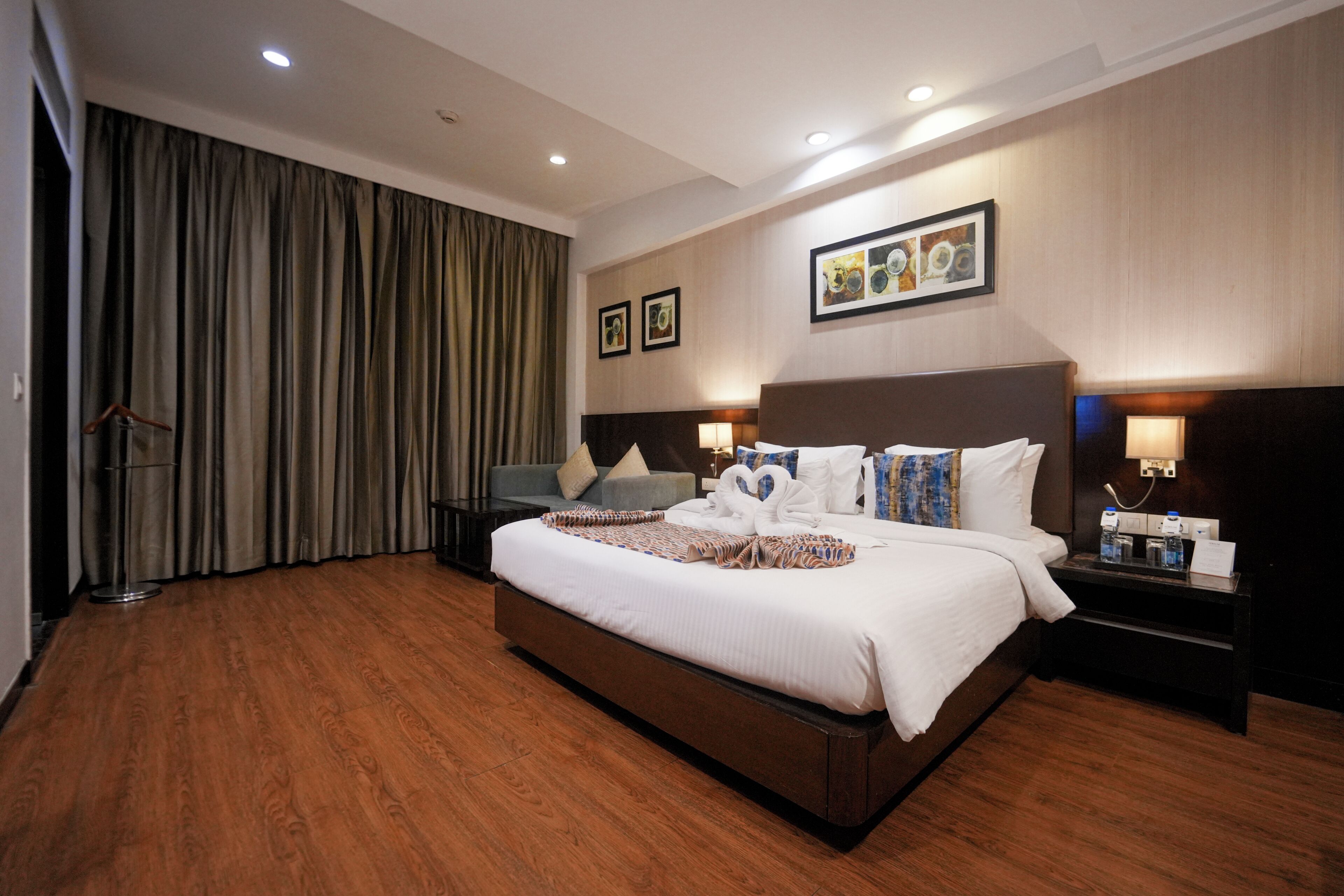 A hotel room with a large bed, a desk, a chair, a wardrobe, and a curtain.