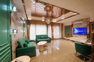Una sala de estar moderna con un sofá verde, una mesa de centro redonda y un televisor de pantalla plana montado en la pared.