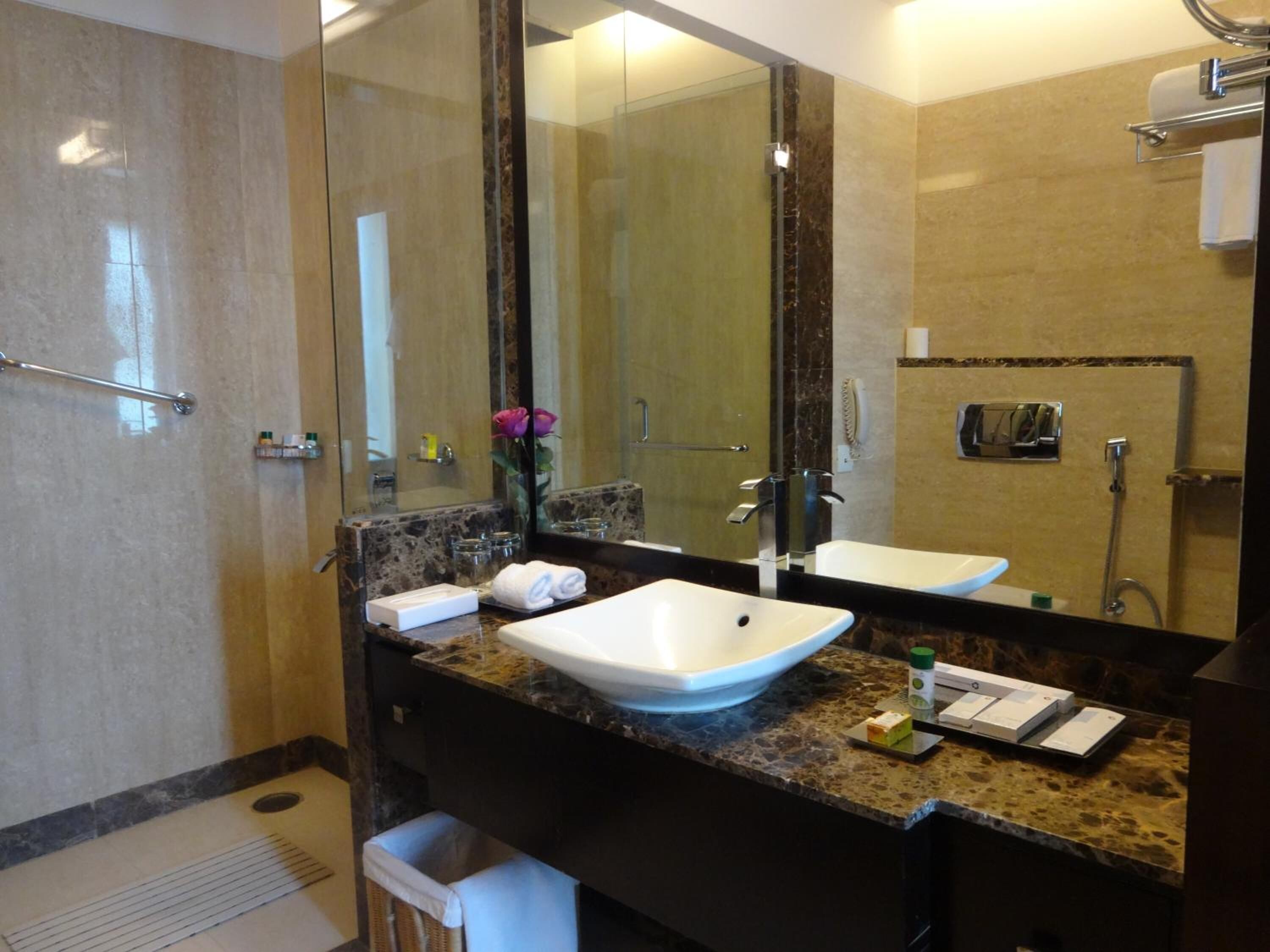 Un baño moderno con un espejo grande, dos lavamanos, una ducha y un perchero para toallas.