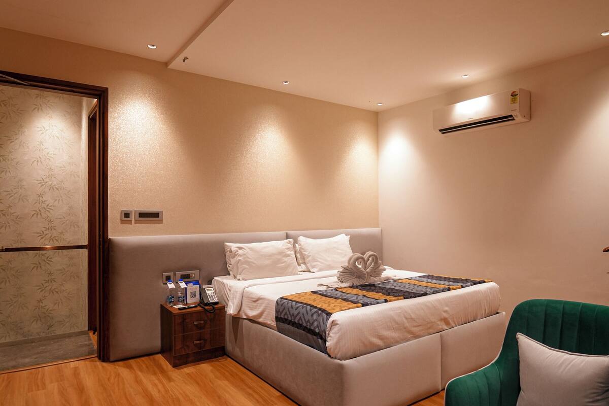 Ein modernes Hotelzimmer mit einem Bett, einem kleinen Tisch und zwei grünen Sesseln.