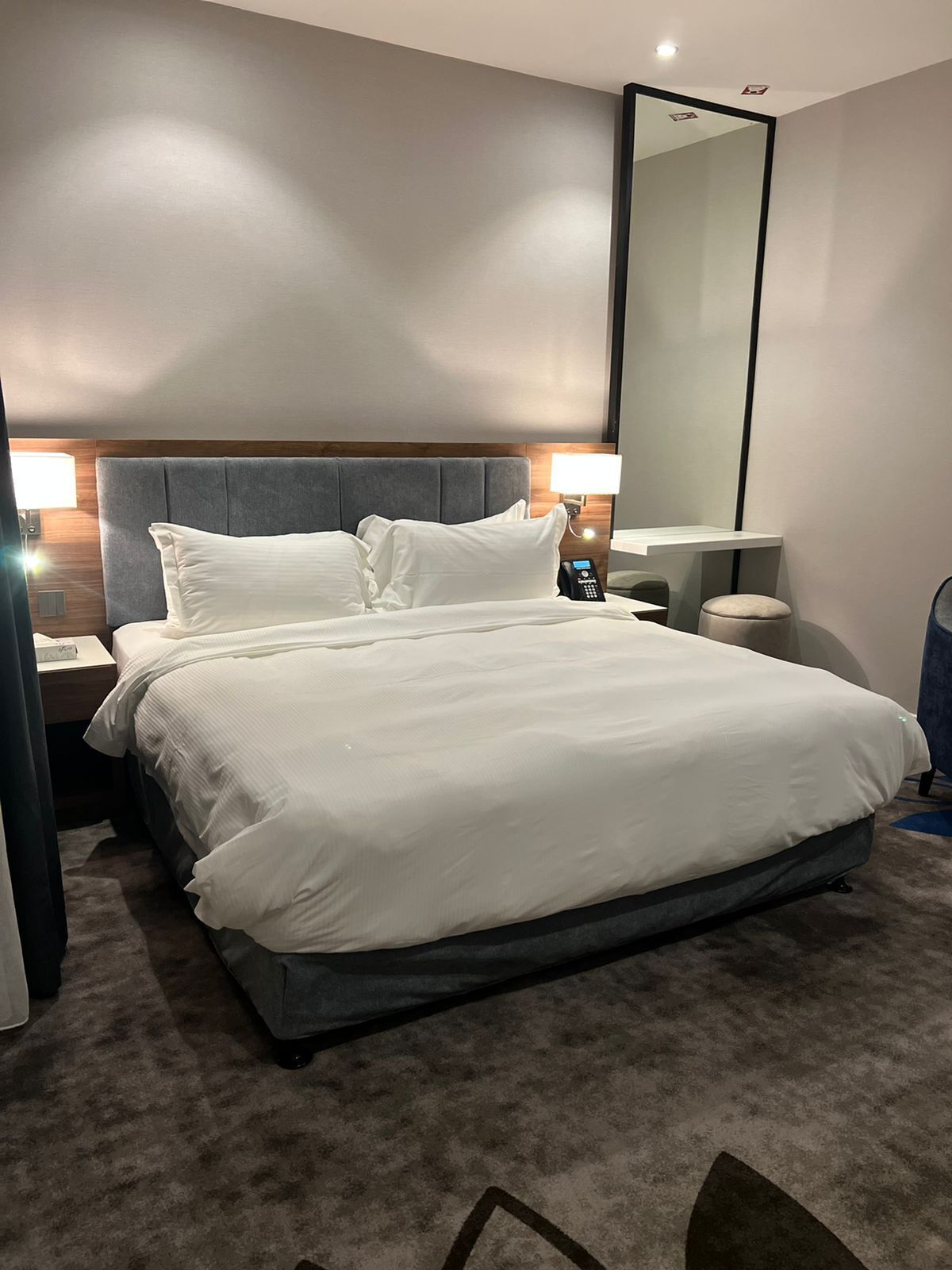 A neatly made bed with white linens in a modern hotel room.