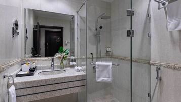 Une salle de bain moderne avec une douche à parois de verre, un comptoir en granit et un miroir.