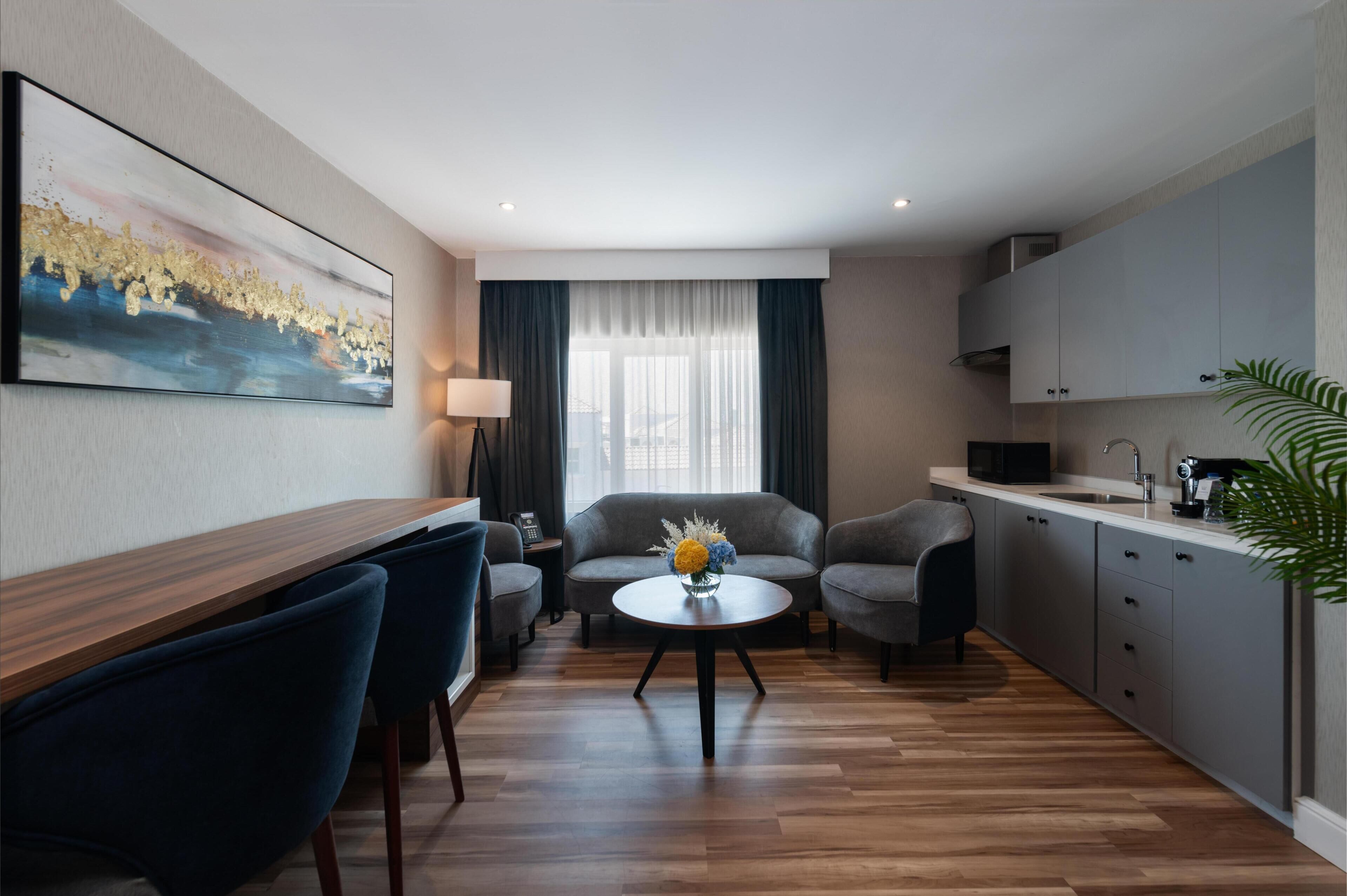 Una habitación de hotel moderna con comedor, sofá y cocina.