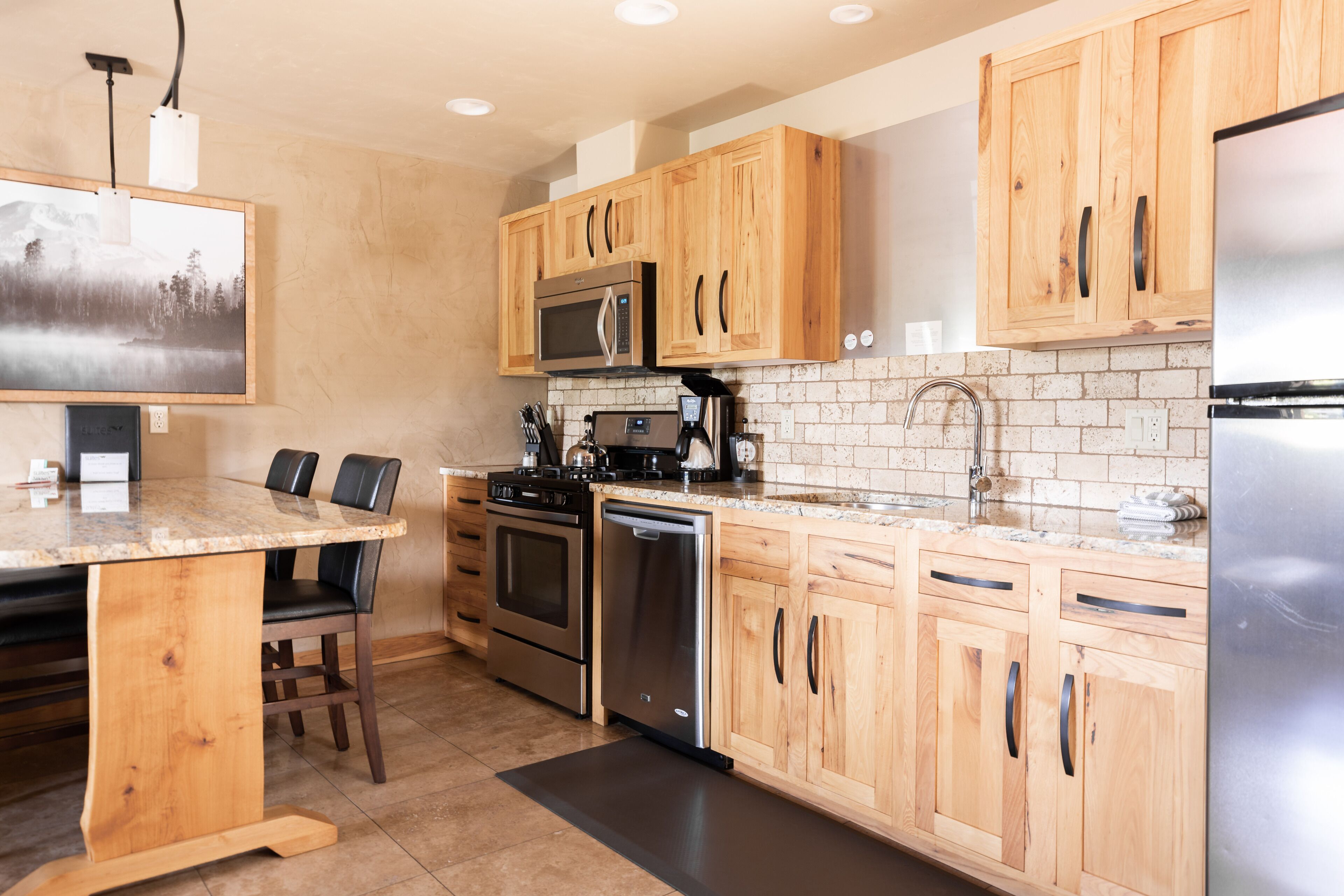 A modern kitchen with wooden cabinets, stainless steel appliances, and a granite countertop.