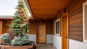 Ein hölzernes Gebäude mit Holztür, einem Fenster und einem Pflanzgefäß mit Pflanzen.