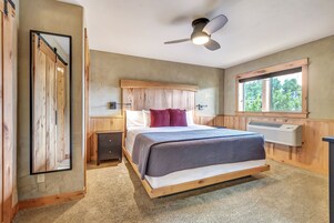 Une chambre à coucher comprenant un lit, un ventilateur de plafond, une fenêtre et un radiateur fixé au mur.