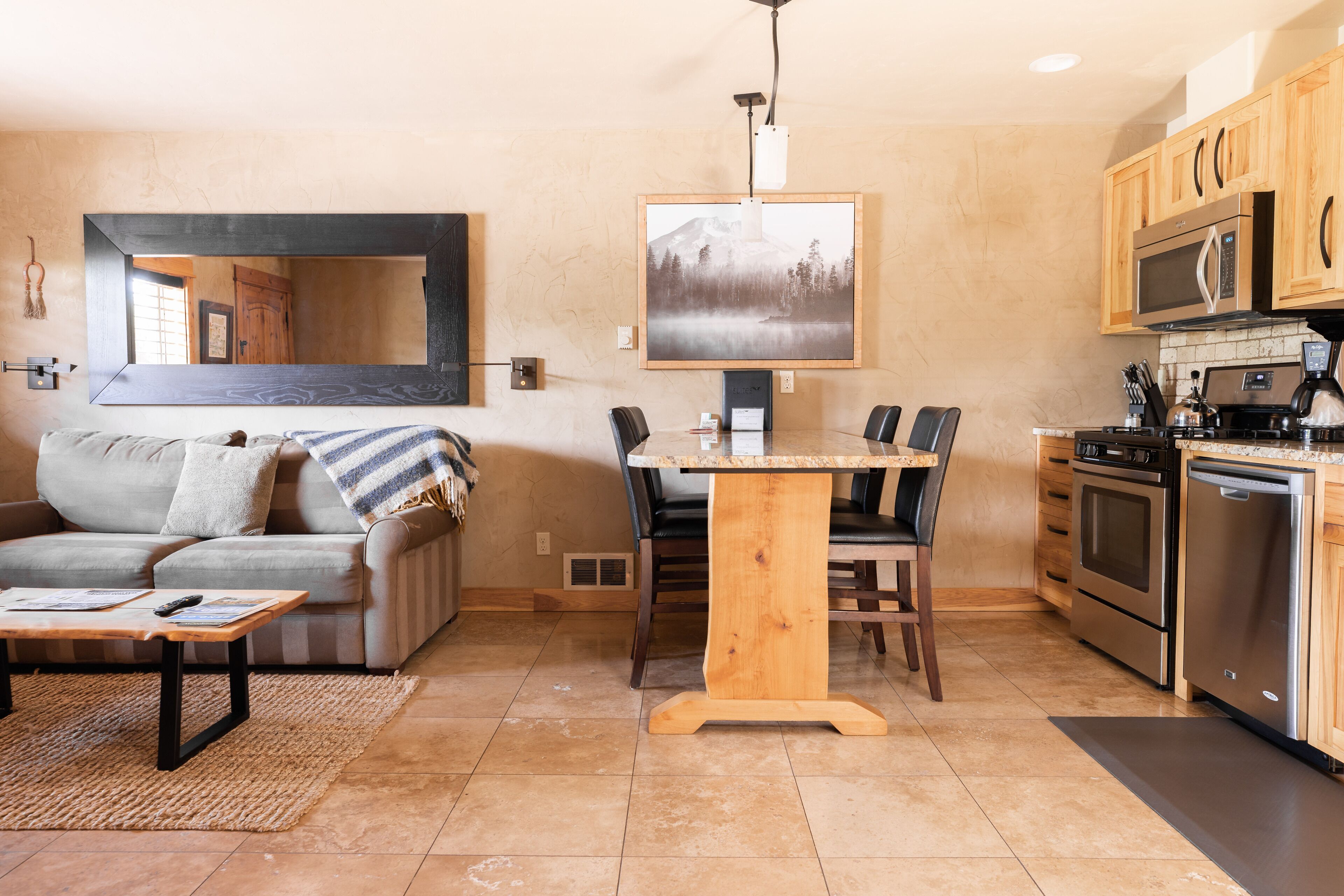 A modern kitchen with a dining table, wooden cabinets, and stainless steel appliances.