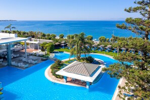 A resort with a large swimming pool, lounge chairs, and a view of the sea. - Oceanis Hotel (Rhodes)