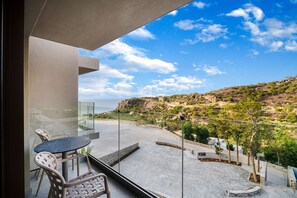 A balcony with a glass door, a round table, and two chairs. - Harmony E Rock Hotel (Ierapetra)