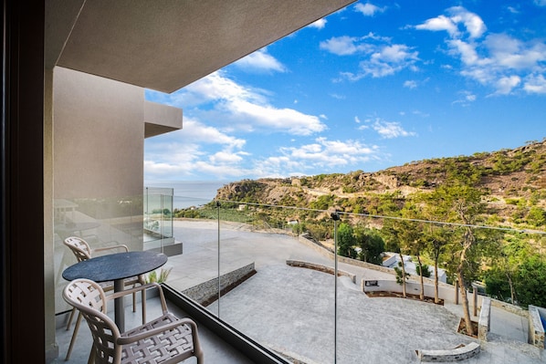 A balcony with a glass door, a round table, and two chairs. - Harmony E Rock Hotel (Ierapetra)