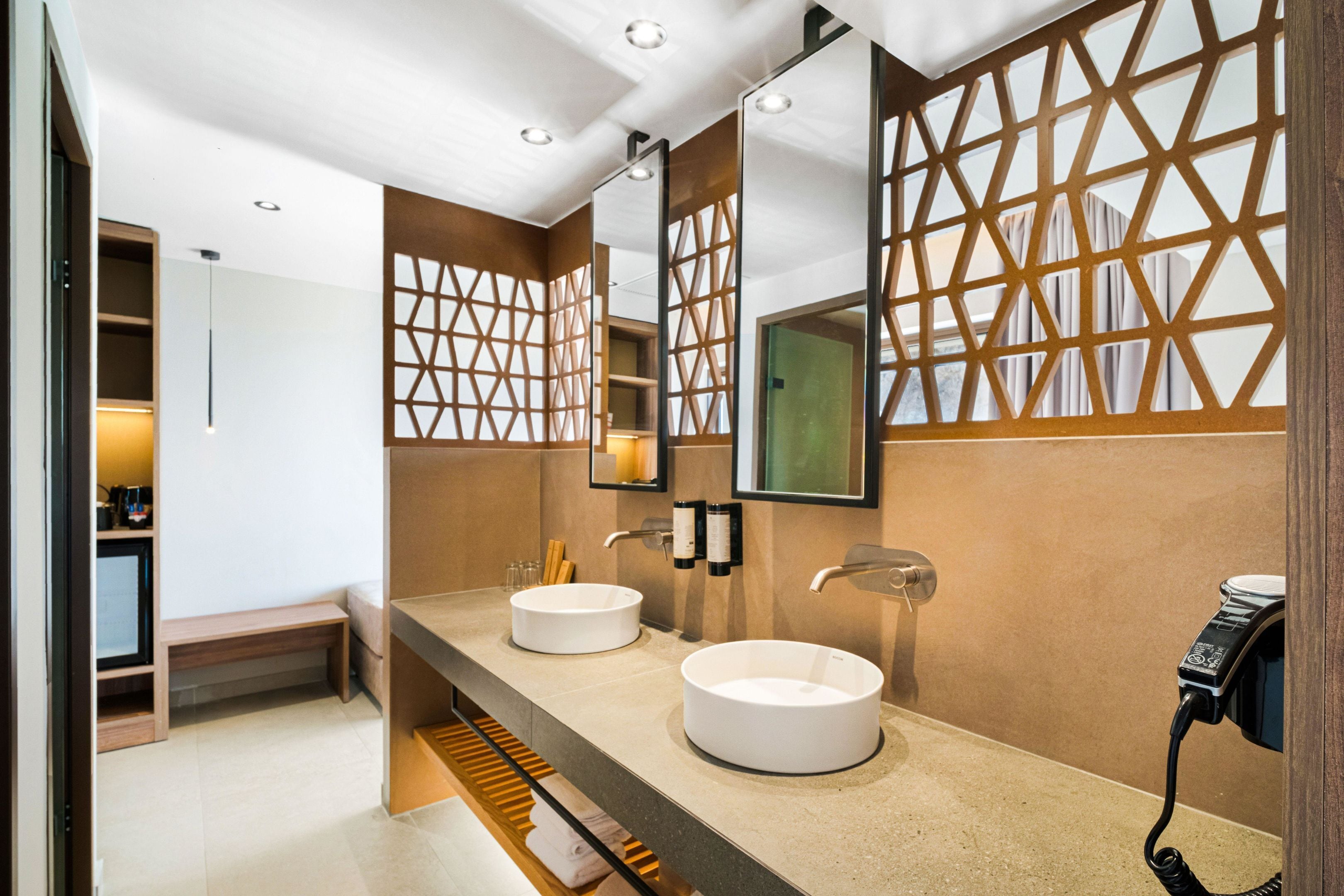 A modern bathroom with two round sinks, a mirror, and a towel rack.
