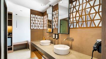 A modern bathroom with two round sinks, a mirror, and a towel rack.