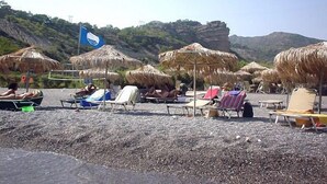 A beach with thatched umbrellas and sun loungers. - Harmony E Rock Hotel (Ierapetra)