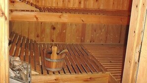 A wooden sauna with benches and a wooden bucket. - Harmony E Rock Hotel (Ierapetra)