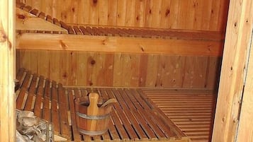A wooden sauna with benches and a wooden bucket.