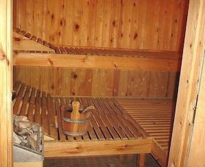 Relax in a serene sauna with a wooden bench and amenities for soaking.