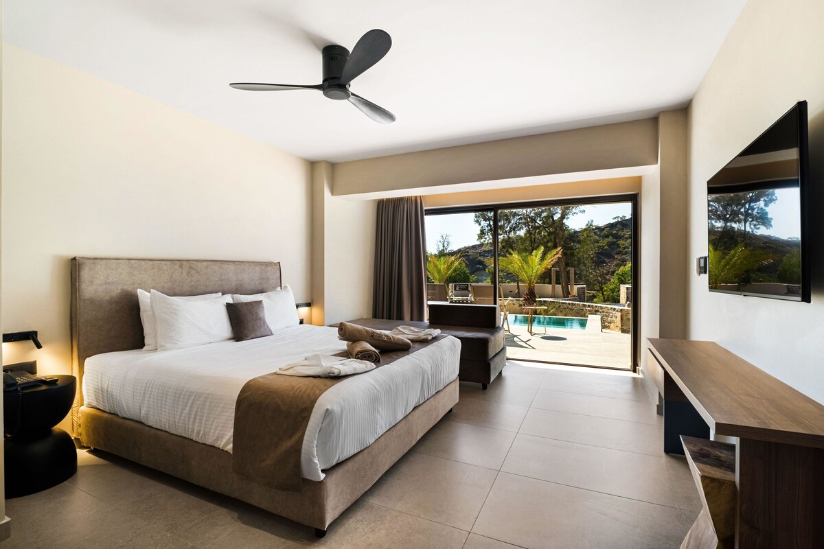 Een moderne hotelkamer met een groot bed, een plafondventilator, een televisie en een balkon met uitzicht op een zwembad.