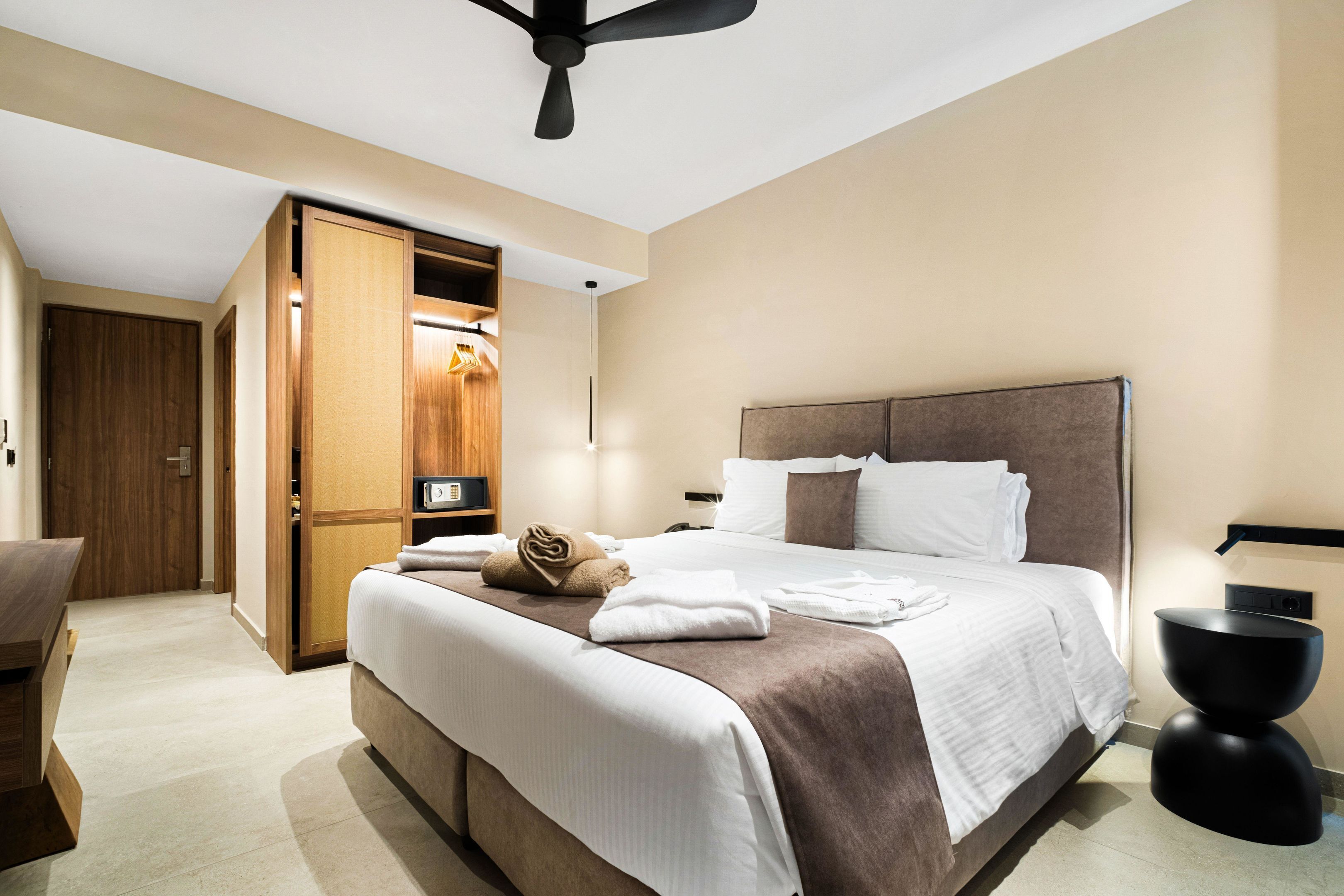 Una habitación de hotel moderna con una cama grande, un armario y un ventilador de techo.