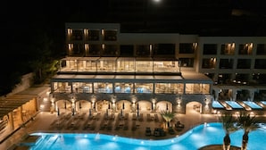 Un hotel de varios pisos con piscina, zona de estar al aire libre y una terraza bien iluminada.