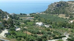 A coastal village with buildings surrounded by greenery and a rocky cliff. - Harmony E Rock Hotel (Ierapetra)