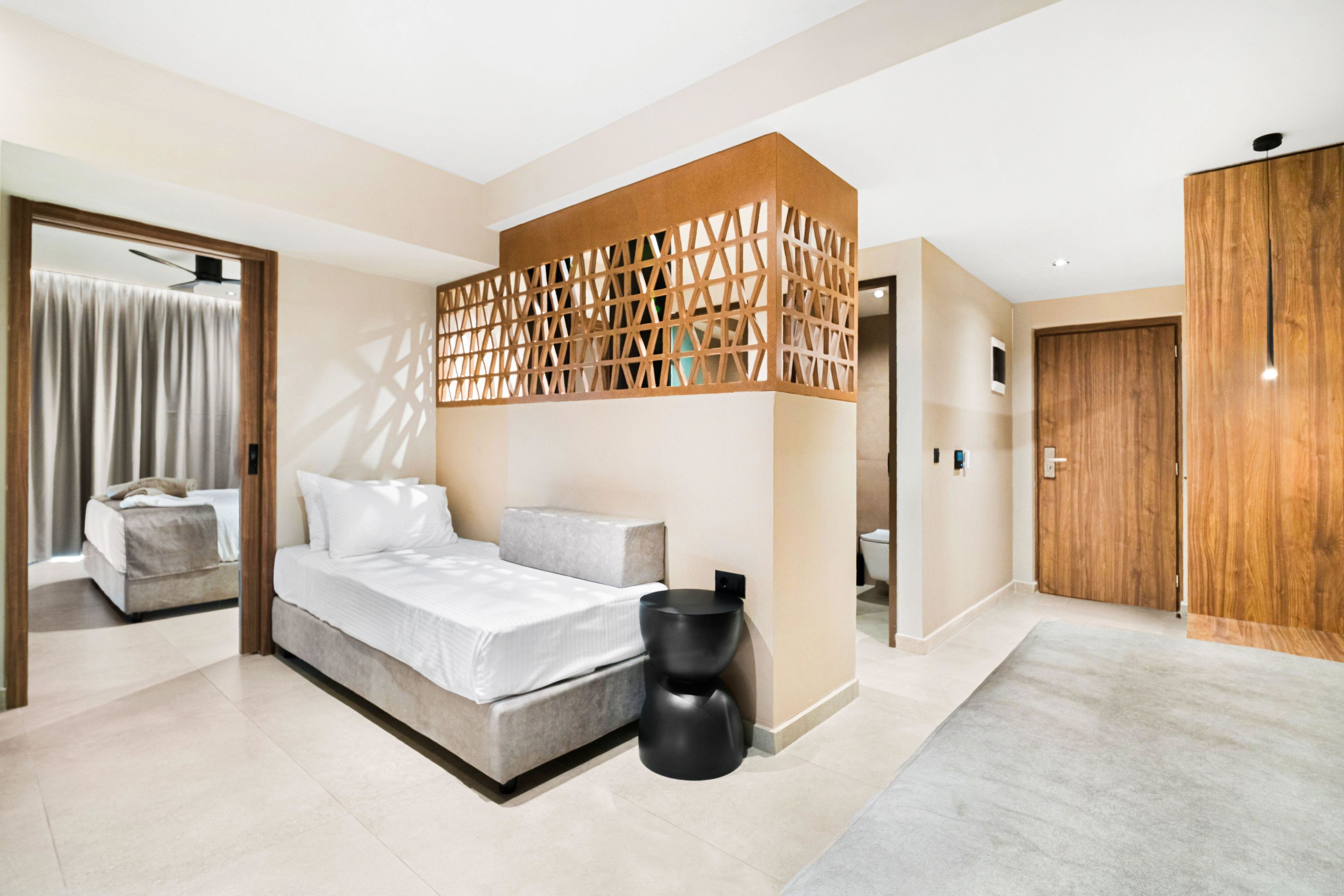 A modern bedroom with a bed, a wooden partition, and a wardrobe.