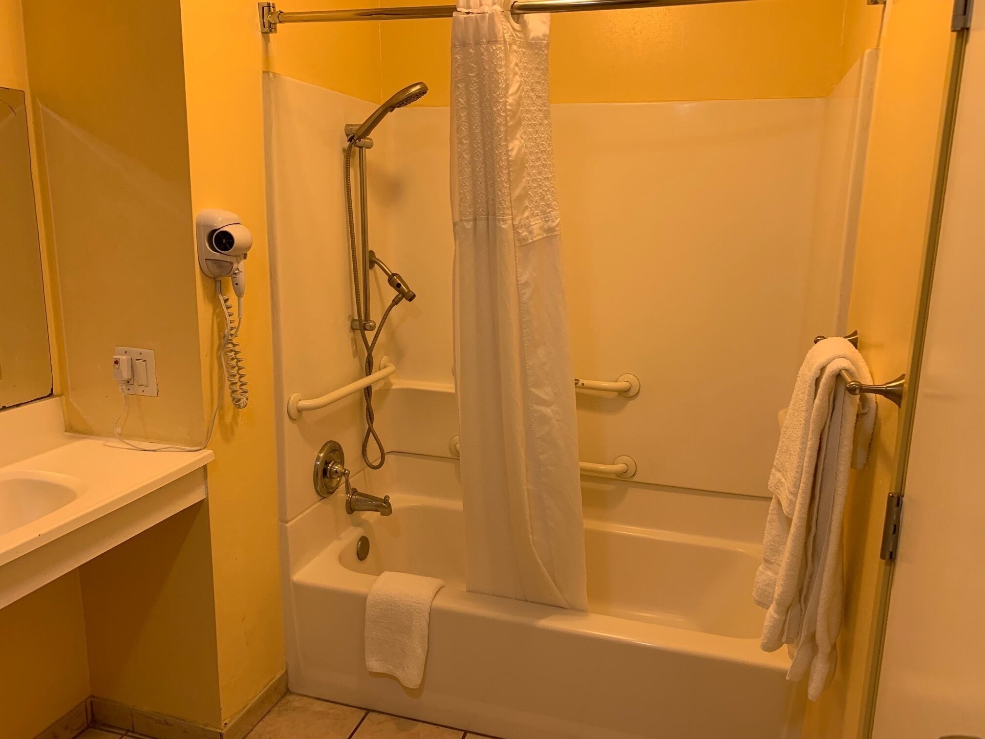 Un baño con bañera, ducha, secamanos y toallero.
