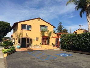 A two-story yellow building with a wheelchair-accessible parking space marked with blue lines and a wheelchair symbol.