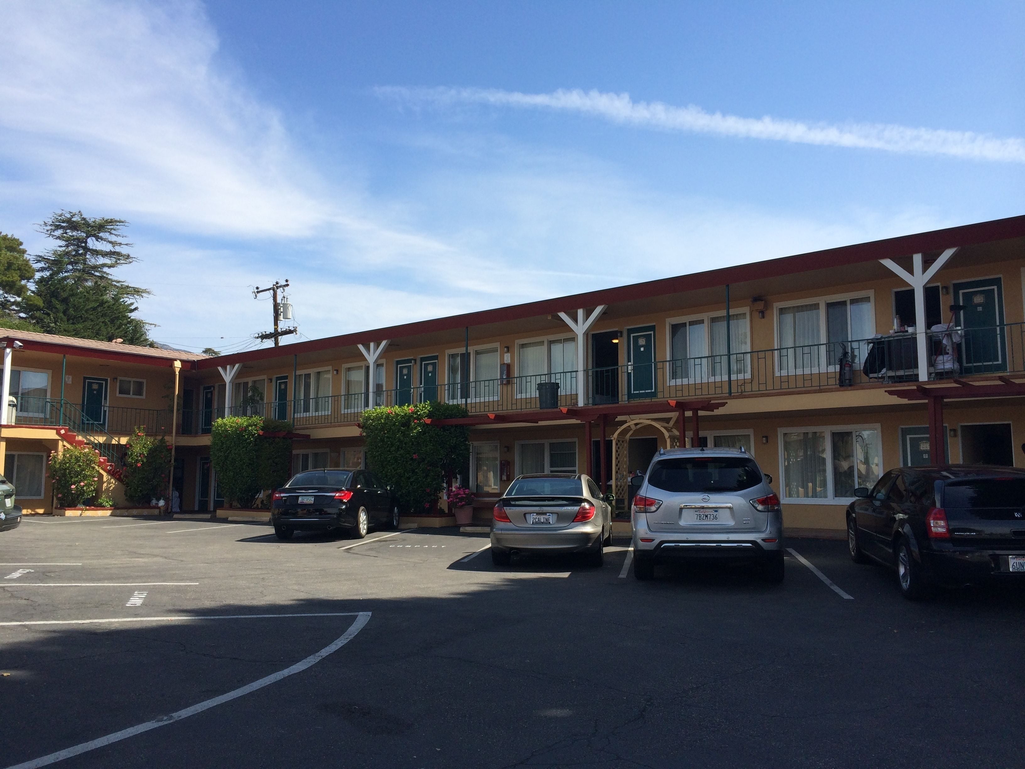 A motel with multiple floors, a parking lot with several cars, and a clear sky.