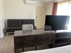 A hotel room with a sofa, a small table, a television, and a door with a lock.