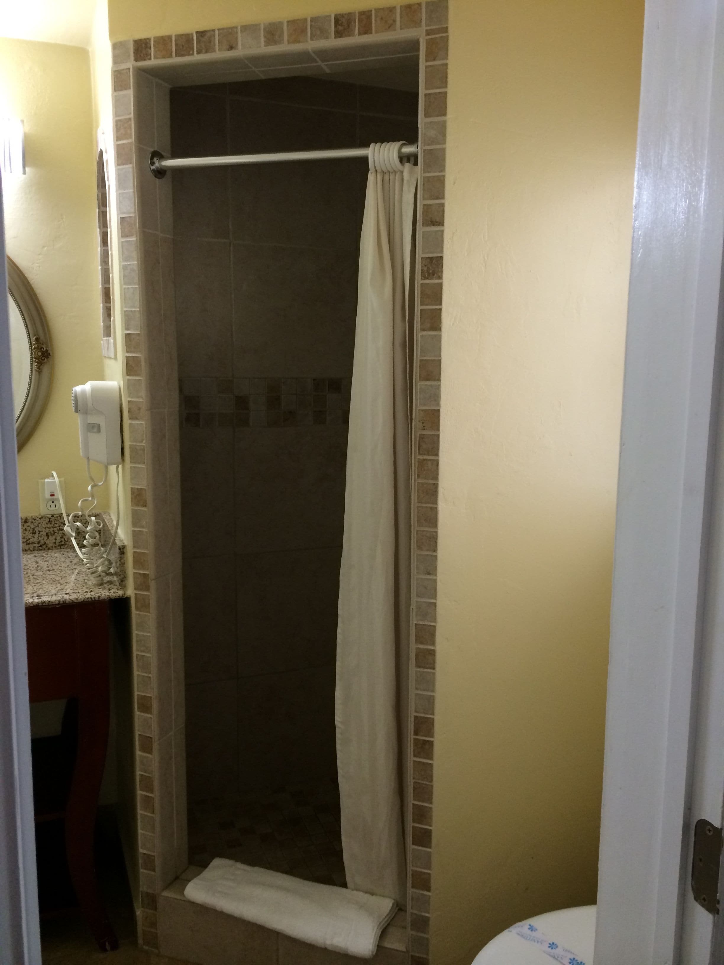 A bathroom with a shower, a towel rack, and a hairdryer on the counter.
