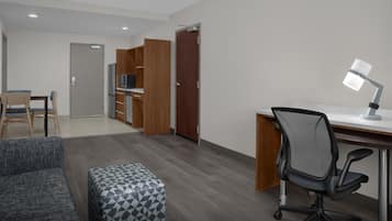 A modern hotel room with a desk, office chair, and a small sofa.