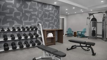 Un gimnasio con banco, mancuernas y máquinas de pesas.