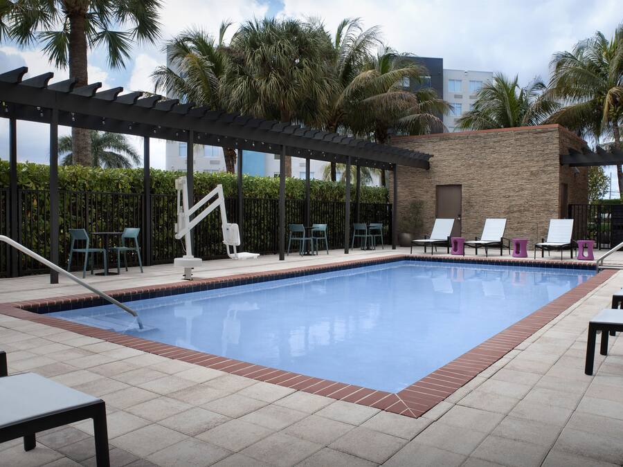 Una piscina con sillas de descanso y una pérgola.