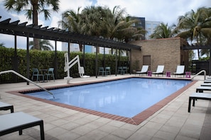Une piscine avec des chaises longues et une pergola.