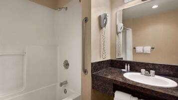 A bathroom with a white bathtub, a sink, and a mirror.