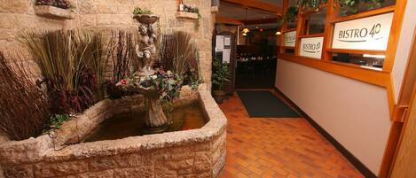 A stone wall with a water feature, potted plants, and a sign for Bistro 40.
